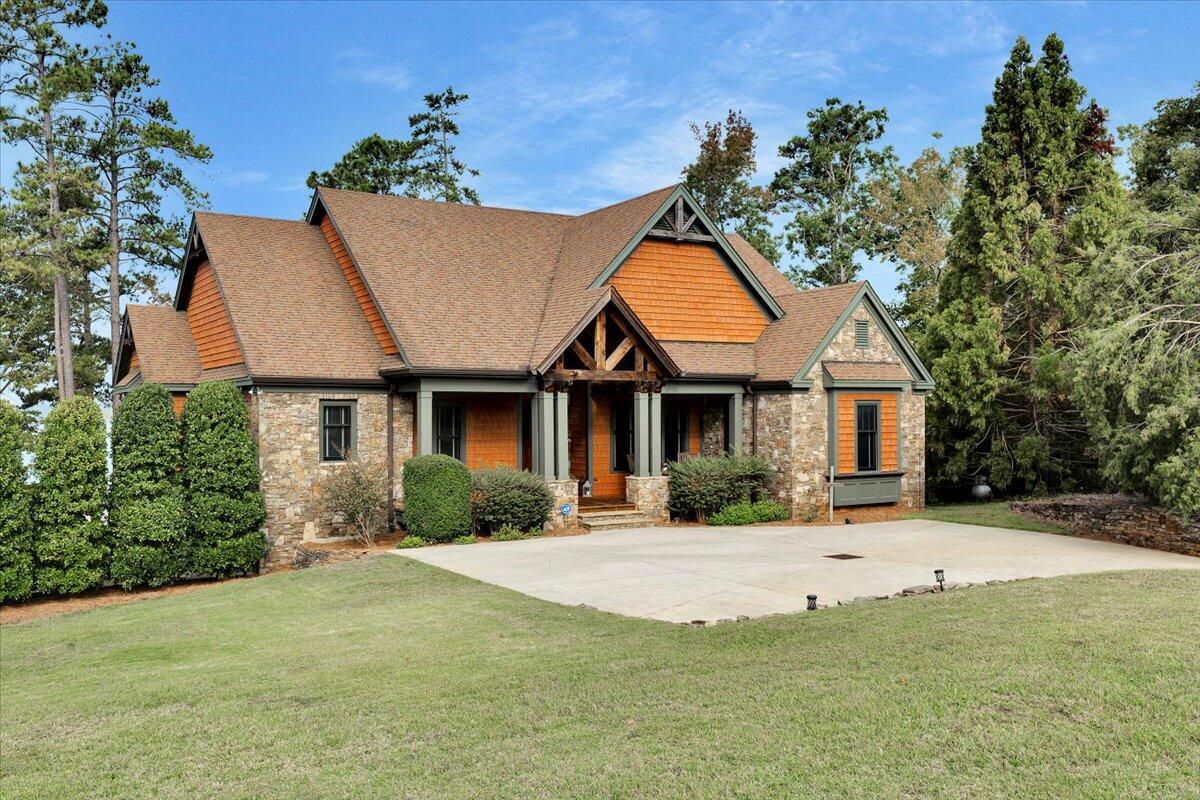 This rarely available home on Breckenridge with its custom build features, astonishing view of Clarks Hill/Strom Thurmond Lake and breathtaking sunsets is a must see! The home features vaulted ceilings, numerous built-ins, and a 2nd indoor kitchen in the finished basement. The eat in kitchen on the main has a large gas range, built in convection oven, wine cooler, ice maker, SS appliances, custom cabinetry galore and a unique backsplash to tie it all together. It is open to a keeping room with a very custom ceiling and living room with lots of windows to get all the natural light. The living room has a grand stone fireplace as a focal point when not looking outdoors at the panoramic view. A master suite features a direct access to the huge screened in porch, a cedar ceiling design straight from historical Augusta, his/her custom closets flank the hallway walking into a luxury bathroom with a tiled steam shower , his/her sinks, and a deep extra large soaking tub all surrounded with a French inspired  shiplap. Off of the main level living area boast a grand screened in  porch with remote drop down shade screens. The outside entertaining areas add over 1600 square feet too this incredible well planned home. Downstairs in the finished basement the family room boast an amazing view as well.  A 2nd kitchen, in the basement, leaves you with more custom cabinetry, a large sink with double ovens, microwave, dishwasher and refrigerator.  Two bedrooms run off the family room leading to their own walk in closets and large bathrooms. One bedroom has its own private access to the outside stone patio. The third bedroom off the family room is an extra large space with a fun accent wall design. This is ideal for a kids room filled with bunkbeds. It has its own  private bath and large walk in closet.  Also accessible to the kitchen and family room is the garage access, a large screened outdoor summer kitchen with antique sink, gas hookup and ceiling fans.
The flagstone patio is large for entertaining family and friends. While taking in the view a stone firepit in ready for that evening fire. A flagstone walk ways direct you down to a two story, partially covered double slip boat dock with two lifts. The other stone walk leads to a  beautiful beach.  An outdoor shower is a short walk around the side of the house next to the 42 foot long garage entrance as well as the second driveway.  Don't delay in making your appt for a private tour today!