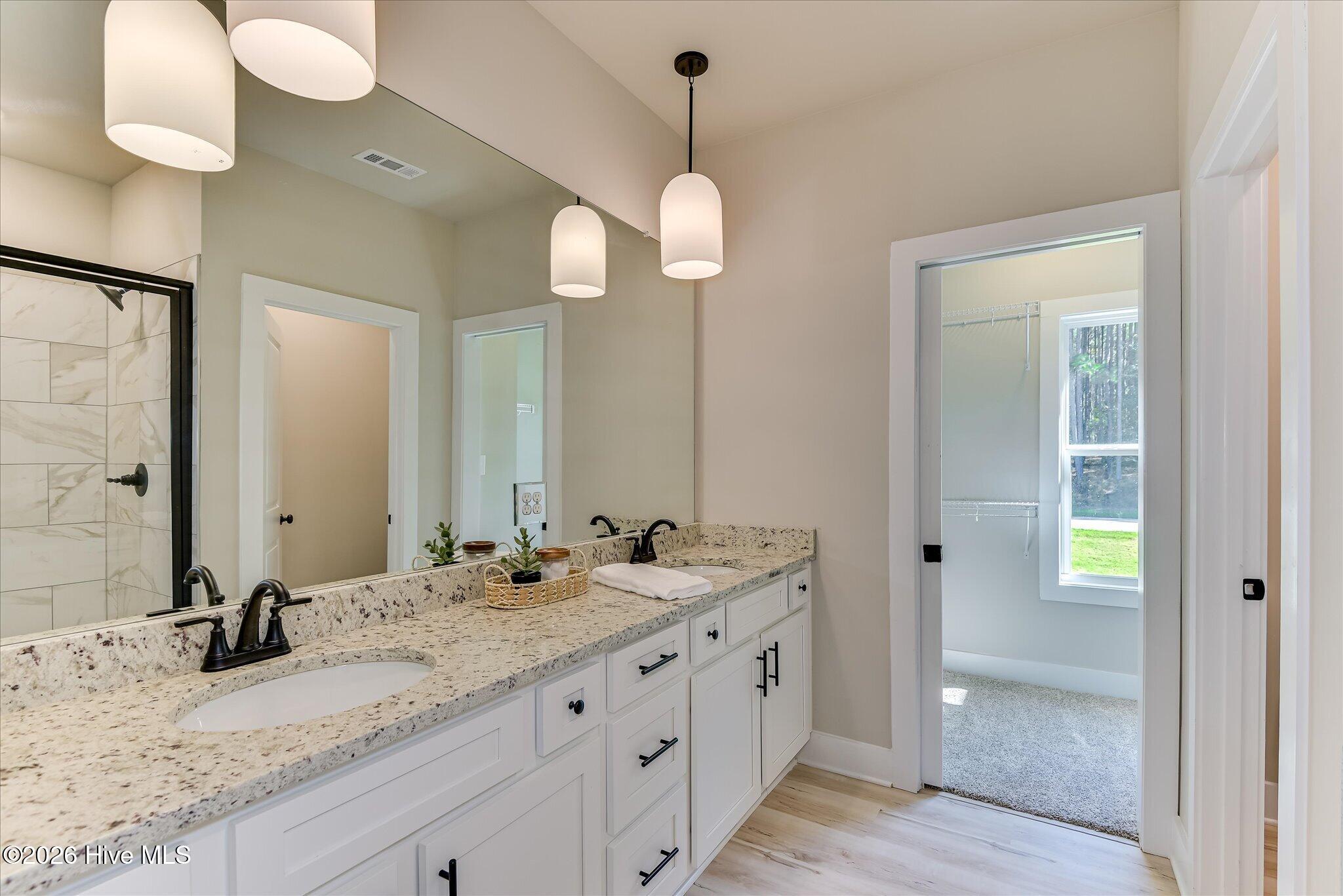 Primary Ensuite with double-sink vanity, tile shower, large walk-in closet