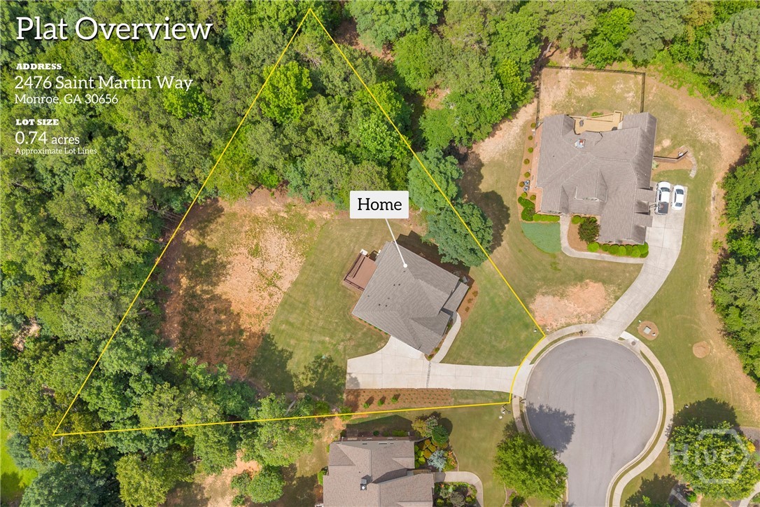 Aerial overview of a 0.74-acre lot featuring a single-story residence with a gray shingled roof, an attached deck, and a concrete driveway