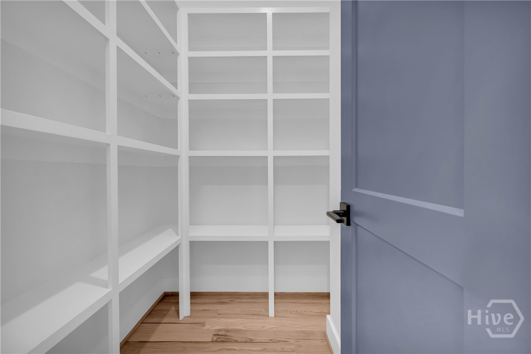 Custom built-in shelving with white finishes, wood-finish flooring, and a contemporary panel door with matte black hardware
