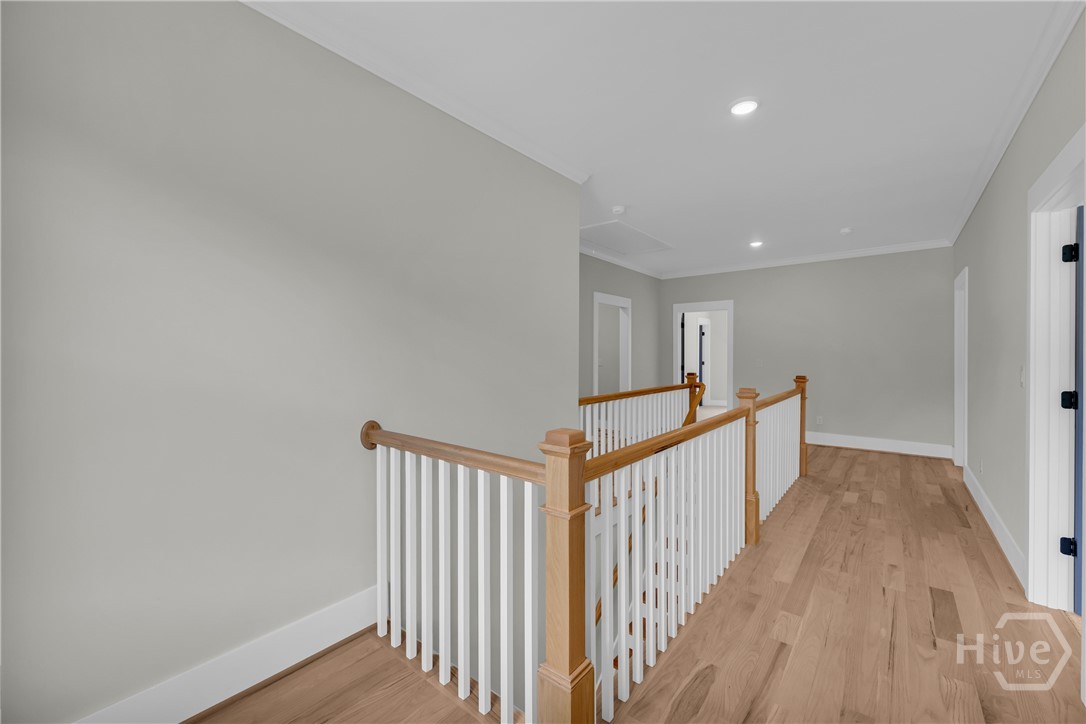 Upper-level hallway featuring wood-finish flooring, white baluster railing with wood newel posts, recessed lighting, and panel doors with dark hardware
