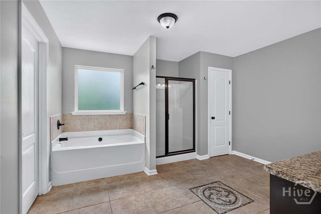 En suite bathroom featuring double sinks, commode room, separate shower and soaking tub