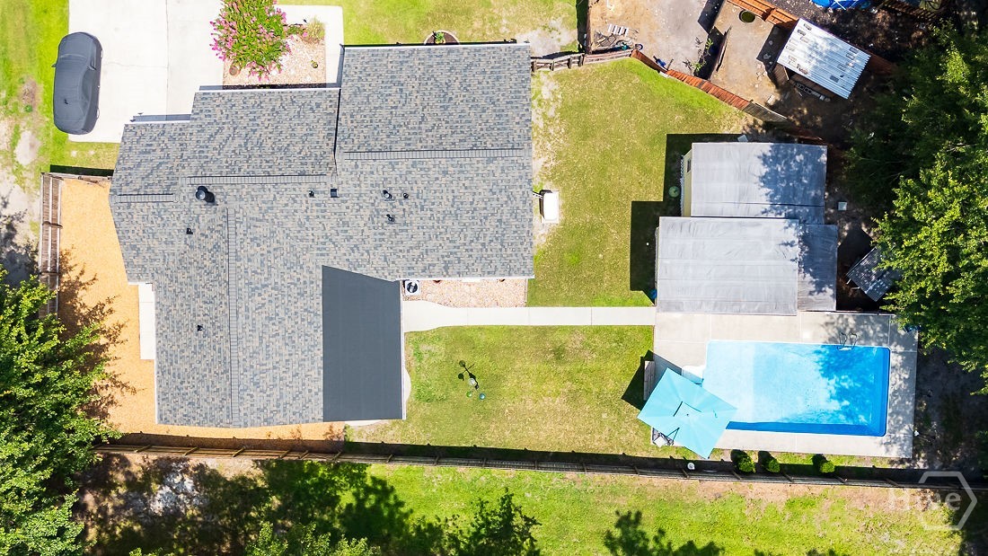 Showing the new roof, pool, fenced yard with tree buffer and pool house.