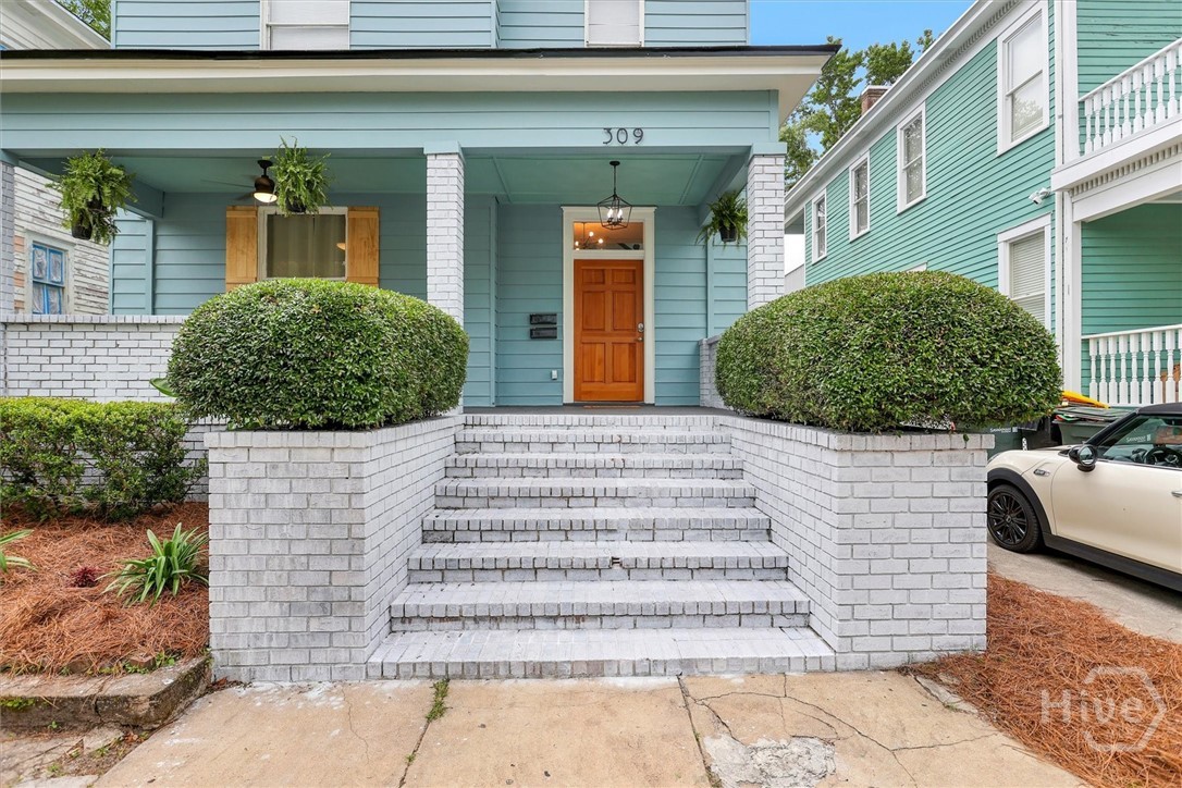 Charming front porch entry with classic brick steps, manicured hedges, and inviting curb appeal.