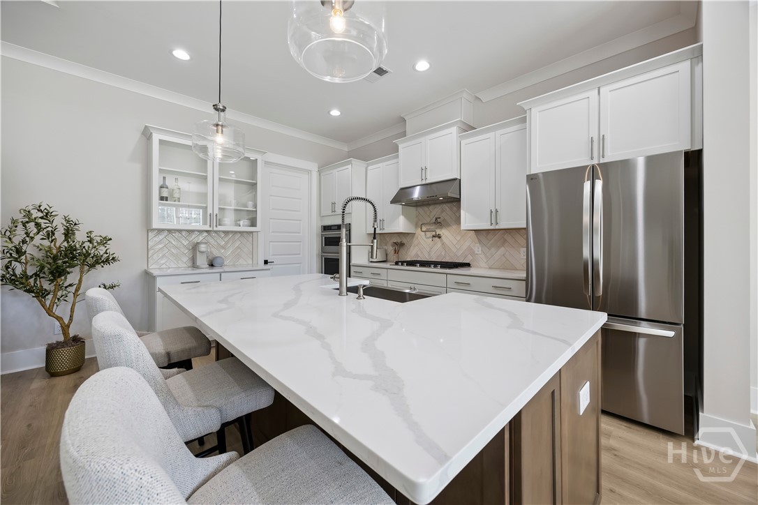 Upgraded kitchen with gas cooktop, double ovens, pot filler, and large center island.