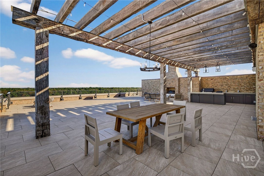 A thoughtfully designed rooftop terrace integrates a rustic pergola, built-in kitchen, and scenic landscape views. The dining zone is anchored by a wood table and chandelier lighting, while stone and brick elements enhance texture. An inviting space for alfresco dining and relaxed luxury - for the most discriminating buyer.