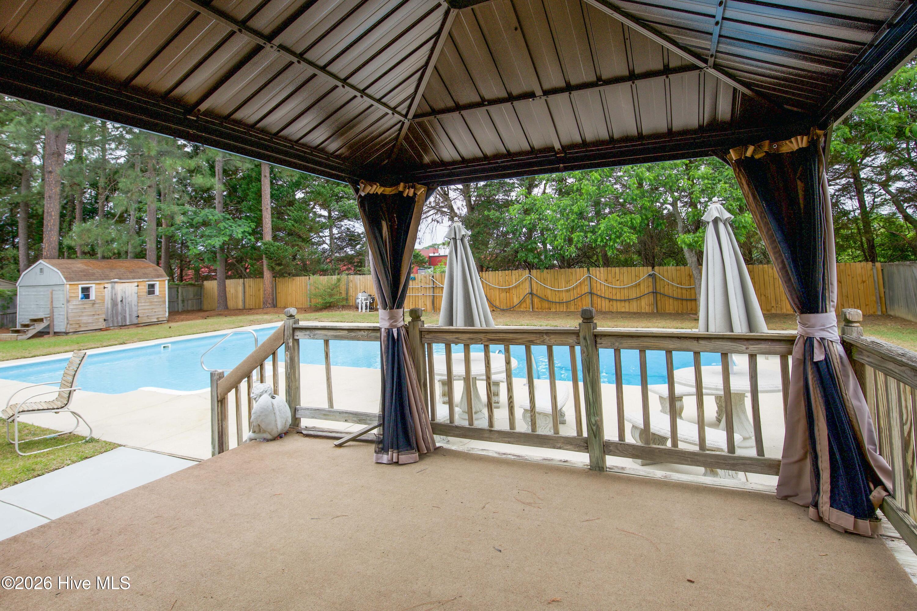 Resort-inspired outdoor entertaining setup featuring a covered gazebo with direct views of the in-ground pool and expansive patio areas. This thoughtfully designed backyard layout offers multiple entertaining zones for relaxing, dining, grilling, or enjoying time outdoors with family and guests. Homes with outdoor lifestyle features, pools, and no HOA restrictions continue to attract strong interest from Fayetteville, Fort Bragg, and military relocation buyers.