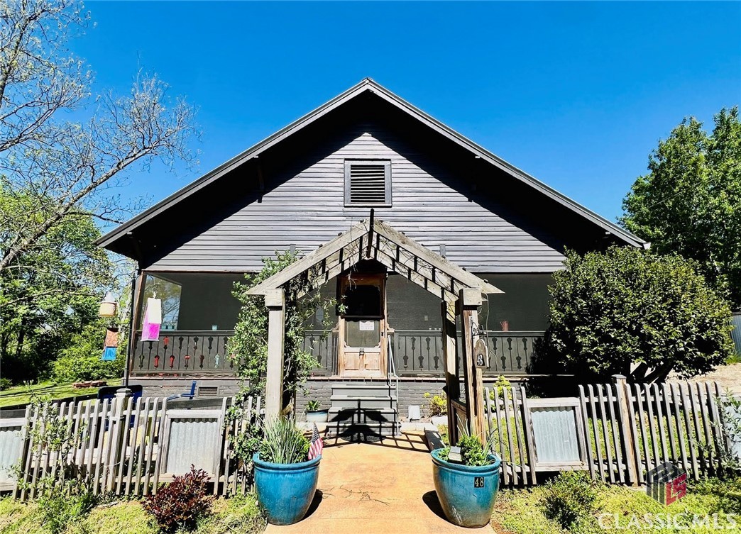 Magazine-Quality, Artfully Restored, Circa 1900 Mill Cottage on .54 acres with lush gardens, perched on a high terraced lot above the Historic Whitehall Mill Lofts, the Oconee River, and on a quiet street of lovingly maintained historic cottages, with arts-centric neighbors. This highly customized property has undergone 2 artful restorations, which have enriched the home’s character and beauty. The current owner has recently done extensive landscaping, adding hundreds of plants, adding abundant parking, including a space next to back door, a fenced front courtyard, a pergola, a storage shed, & landscape screening. This is a corner lot, and there’s a large, flat, and open green space behind house and formal garden beds, which provides wonderful possibilities for an array of uses: recreational space, a pool, guest house, art studio, workshop, office... Inside house, there’s sublime beauty and historic character, conjoined with modern comforts. The entire left side of the cottage is open, front to rear, is common living area, which connects to both front and rear screen porches, all cloaked in abundant natural light. The walls between LR, DR, and Kitchen have been opened up, and hand-hewn antique beams are exposed at each wall opening. The kitchen features: custom-made heart pine cabinets, wood ceilings, stainless appliances, quartz counters, along with reverse osmosis, and soft water, filtering systems. The primary bath is a lovely highlight, a huge room with with: tall wood ceilings, 2 large, South-facing, transom windows flood the room in natural light, a wide heart pine bead-board wainscoting wraps the room and shower, conveying warmth, the shower is artfully tiled with a mix of stone and tile, and there’s an antique claw foot tub, with a hand blown ( by a local artist ), blue glass wall sconce light above the tub. The Primary bedroom has both a walk-in closet and a large secondary closet. The 2nd bedroom has a newly built, on suite, lovely half bath. There are original mantles in LR, DR, and Master BR. The floors are oak, pine, and tile. Honestly, the photos may tell the story of just how unique and special this home is best. Or perhaps, a tour! The landscape almost presents itself as an array of outdoor rooms, each area with its own allure. Again, this is a very unique property, a true treasure, the type of property that’s not easily found, or reproduced. Must be seen to fully appreciate.