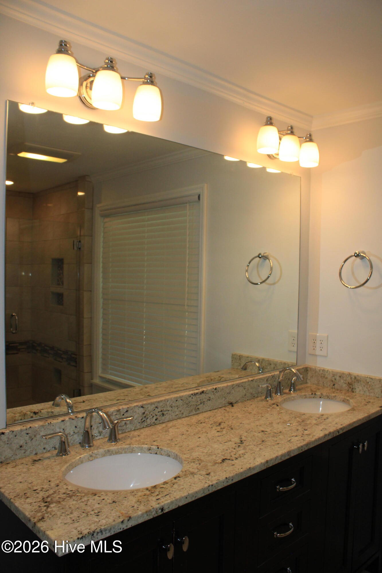 Double vanity w/ granite countertops and oversized mirror.