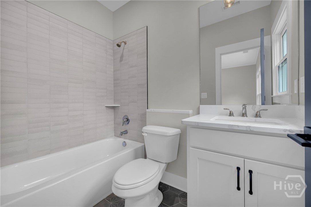 Contemporary bathroom featuring a white vanity with a rectangular undermount sink, a large mirror, and a white bathtub with subway tile surround and a glass shower partition