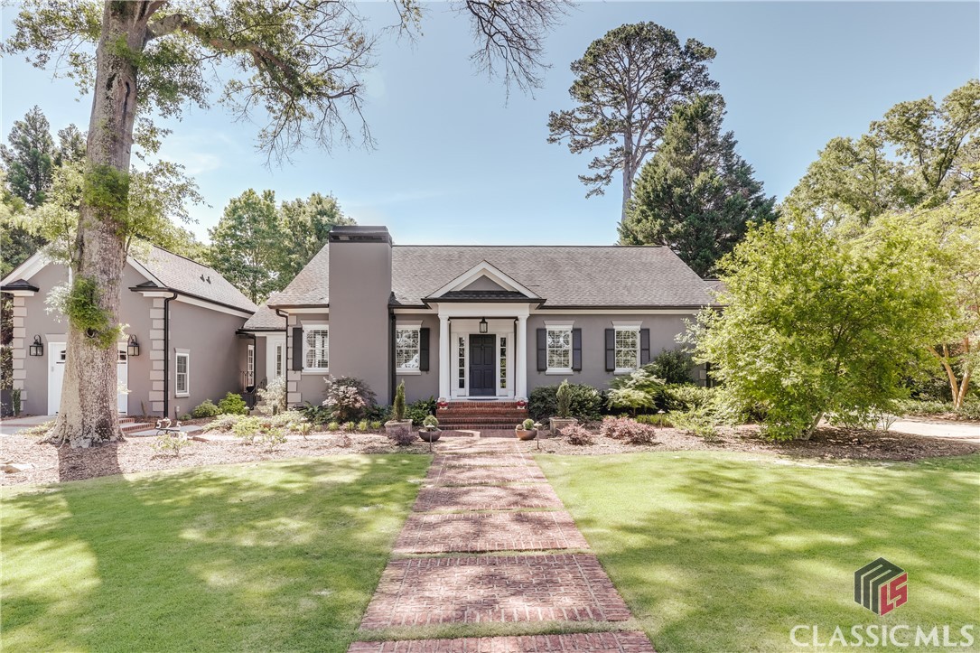 Situated on the most premiere street in Athens, this incredible 4 bedroom/4 bath (1/1 in carriage house) home has been lovingly updated while keeping the prime historic elements of original construction. The high ceilings and grand, formal rooms are casually elegant and provide great flow for entertaining with original beautifully refinished hardwood floors and pristine plaster walls. Approaching the front door, is a beautiful brick walkway with incredible landscaping flanking either side. You walk into a formal foyer entry with a large living space with fireplace and lovely vaulted sunroom with generous floor to ceiling windows and doors. The dining room is ample sized with original built-ins and classic folding doors. The kitchen has been beautifully updated with custom cabinetry, quartz countertops, a sub zero fridge and two freezer drawers.  The kitchen offers additional access to the dreamiest gardens, covered patio with outdoor fireplace, and fenced yard - you will want to live in the backyard alone! The owner's suite on the main level is graciously sized with a private sitting room with additional fireplace, and a fully updated en-suite bathroom with two large vanities, soaker tub, huge separate shower, and a dressing room with private laundry. Beautiful hardwood floors are throughout the home and the original trim has been preserved. Upstairs are two spacious secondary bedrooms with a renovated hall bathroom with a large tile shower and a separate, large laundry. A single car garage with a carriage house above was recently added, and creates the perfect private guest suite! The home is constructed of concrete and hard - coat stucco and is extremely energy efficient. This private oasis is located in the heart of Five Points with extreme walkability to some of the best restaurants, coffee shops, boutiques, and award-winning David C Barrow Elementary School!