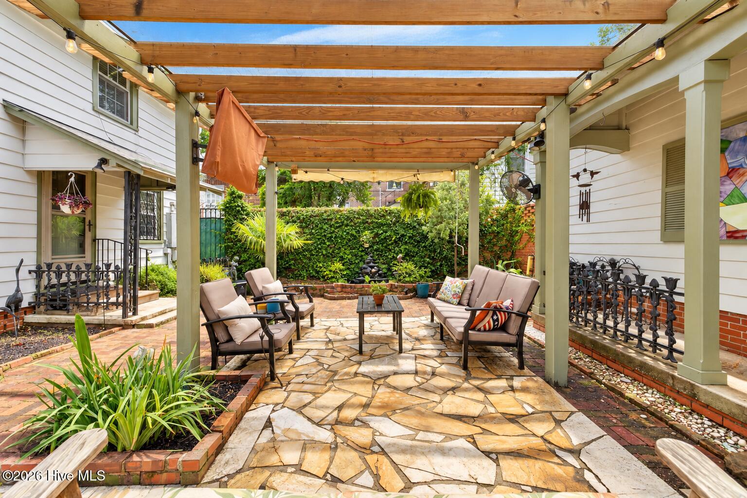 Courtyard with historic bricks and tall walls for privacy. and a shaded trellis for backyard entertaining