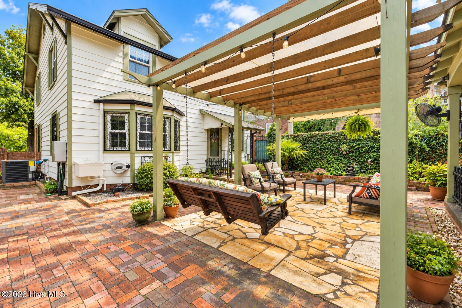 Courtyard with historic bricks and tall walls for privacy. and a shaded trellis for backyard entertaining