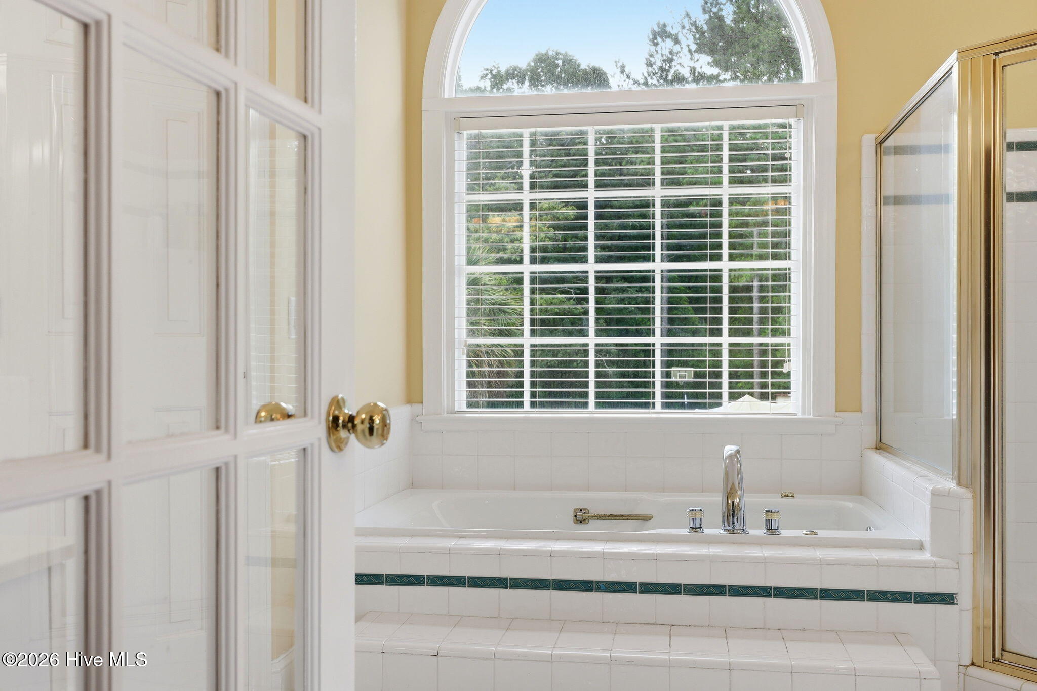 owner soaking bath with arched window overlooking back yard for privacy