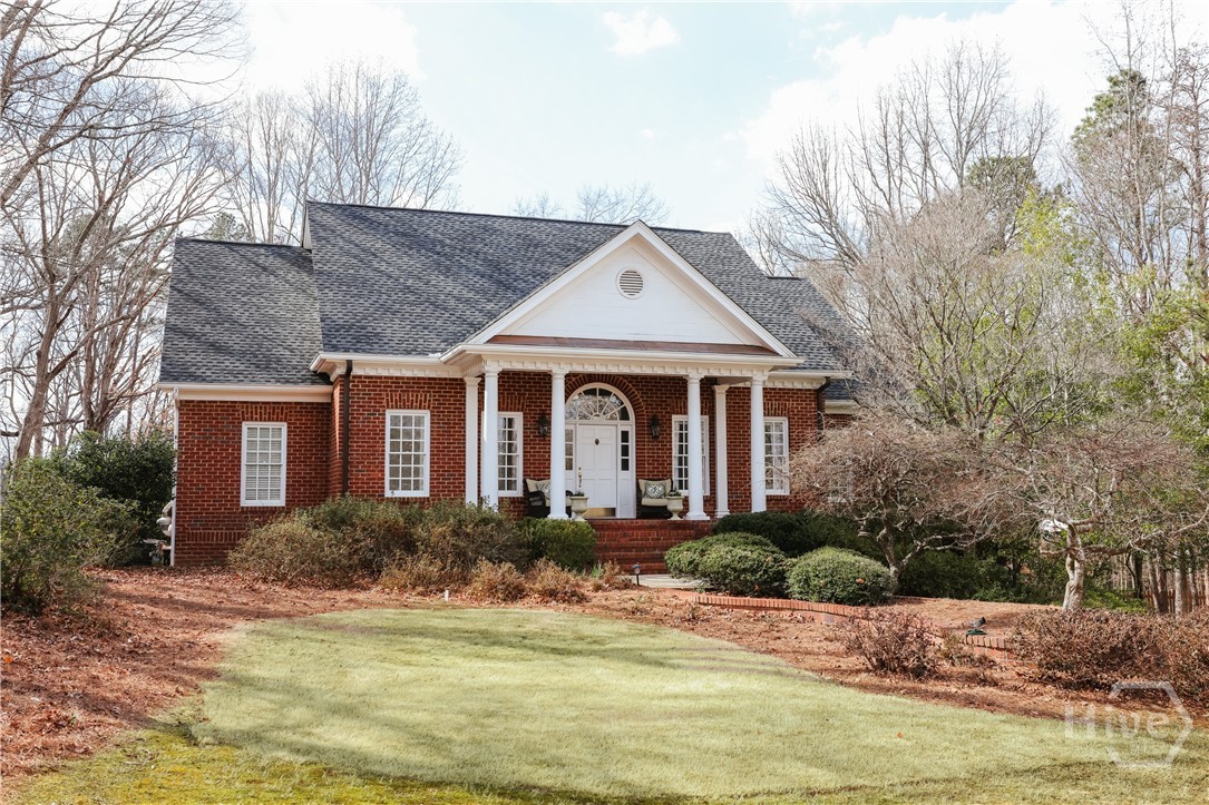 A stately four-sided red-brick home, this beautifully crafted residence offers timeless elegance and gracious living, perfectly sited on 1.84 lush, private acres. A welcoming covered front porch sets the tone for the warmth and refinement found throughout. Inside, the spacious foyer opens to a formal dining room and an oversized great room anchored by a gas fireplace flanked with custom built-ins. French doors extend the living space onto a large deck, ideal for entertaining or quiet enjoyment of the serene surroundings.The main level features a thoughtfully designed primary suite, complete with a well-appointed bath offering dual vanities, a garden tub, and a separate walk-in shower. A dedicated home office provides convenience and flexibility for work or study. The fully remodeled chef’s kitchen is a standout, showcasing bright white cabinetry, new stainless steel appliances including a five-eye gas range, and gorgeous granite countertops that span the functional island and lower cabinets. A generous breakfast area—also suitable as a keeping room—opens through a second set of French doors to the expansive grilling deck, creating a seamless flow for indoor-outdoor living.A rear staircase leads to two upper-level guest suites, each with a large walk-in closet and private en-suite bath. The vaulted, oversized walk-in attic offers exceptional potential for a future sitting room, studio, or flexible bonus space. The finished terrace level enhances the home’s versatility with a comfortable media room, an additional bedroom, and a full bath—perfect for guests or multi-generational living.Additional highlights include a new roof, a three-car garage, and a fully fenced yard. This distinguished home blends traditional architecture with modern comfort, providing abundant space, privacy, and an inviting setting for both everyday living and memorable gatherings.