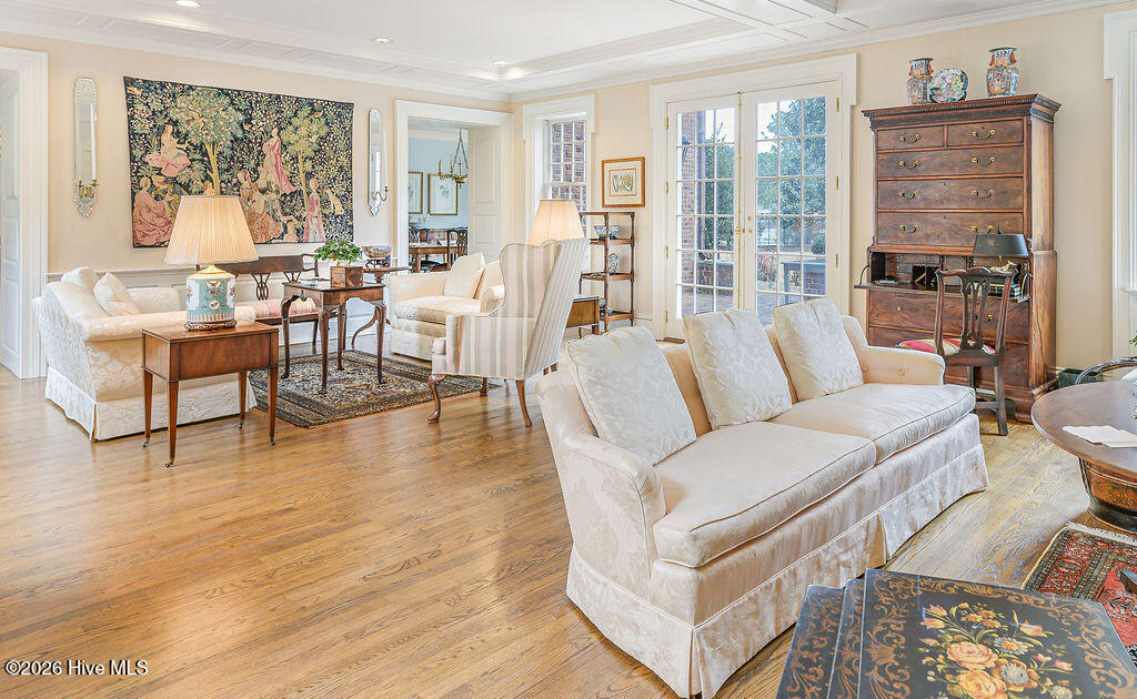 Nearly forty feet long, the drawing room is defined by a Federal-style carved mantel, dark marble surround, coffered paneled ceiling, arched built-in bookcases, and French doors to the rear terrace.