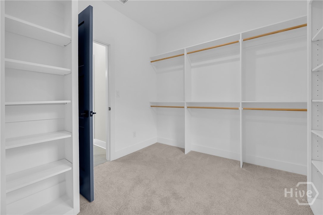 Walk-in closet featuring built-in shelving, hanging rods, and carpet flooring