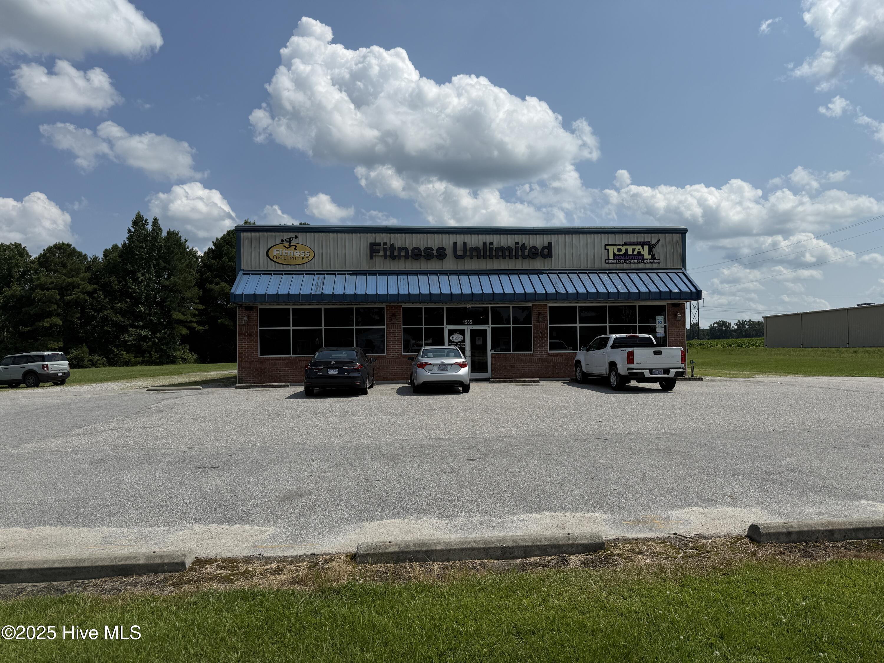 Take advantage of this exceptional opportunity to own a versatile commercial property in the heart of Williamston, NC. Located at 1985 W Main St, this active fitness center sits within the city limits and in a federally designated Opportunity Zone, offering strategic value for investors and entrepreneurs alike. Zoned for commercial use, this 4.2-acre property provides ample space to expand or redevelop. The main building measures 100' x 60', offering 6,000 square feet of heated and cooled space, complete with two garage doors (10'x12' and 10'x15'), men's and women's restrooms and changing rooms, and a layout ideal for a wide range of uses—from auto service and light manufacturing to distribution or retail. An additional 30' x 20' storage shed provides valuable storage or operational flexibility. With 360 feet of road frontage on Old US Highway 64, and a traffic count of 8,400 vehicles per day, the property boasts high visibility and easy access to Highway 125 and US 64—just 1.5 miles away. From here, you're only 1.5 hours to Raleigh and 1.75 hours to Nags Head, making this a centrally located hub for regional operations. Proximity to Martin Community College (only .5 miles away) adds workforce access and local engagement potential. Whether you're looking to expand an existing operation or start something new, this highly visible, adaptable property is packed with potential. Don't miss your chance—schedule a tour today!