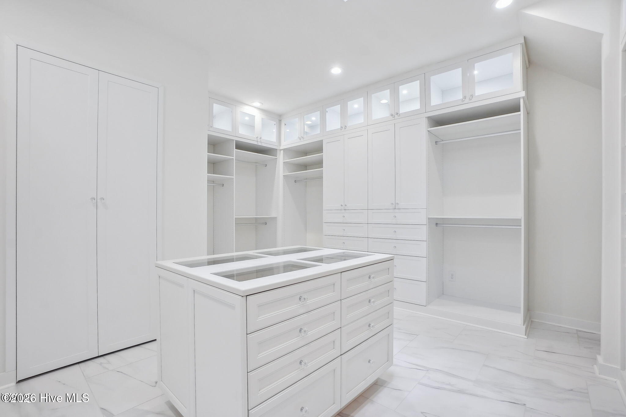 Two story primary closet with custom cabinetry, lighting and two floor chandelier