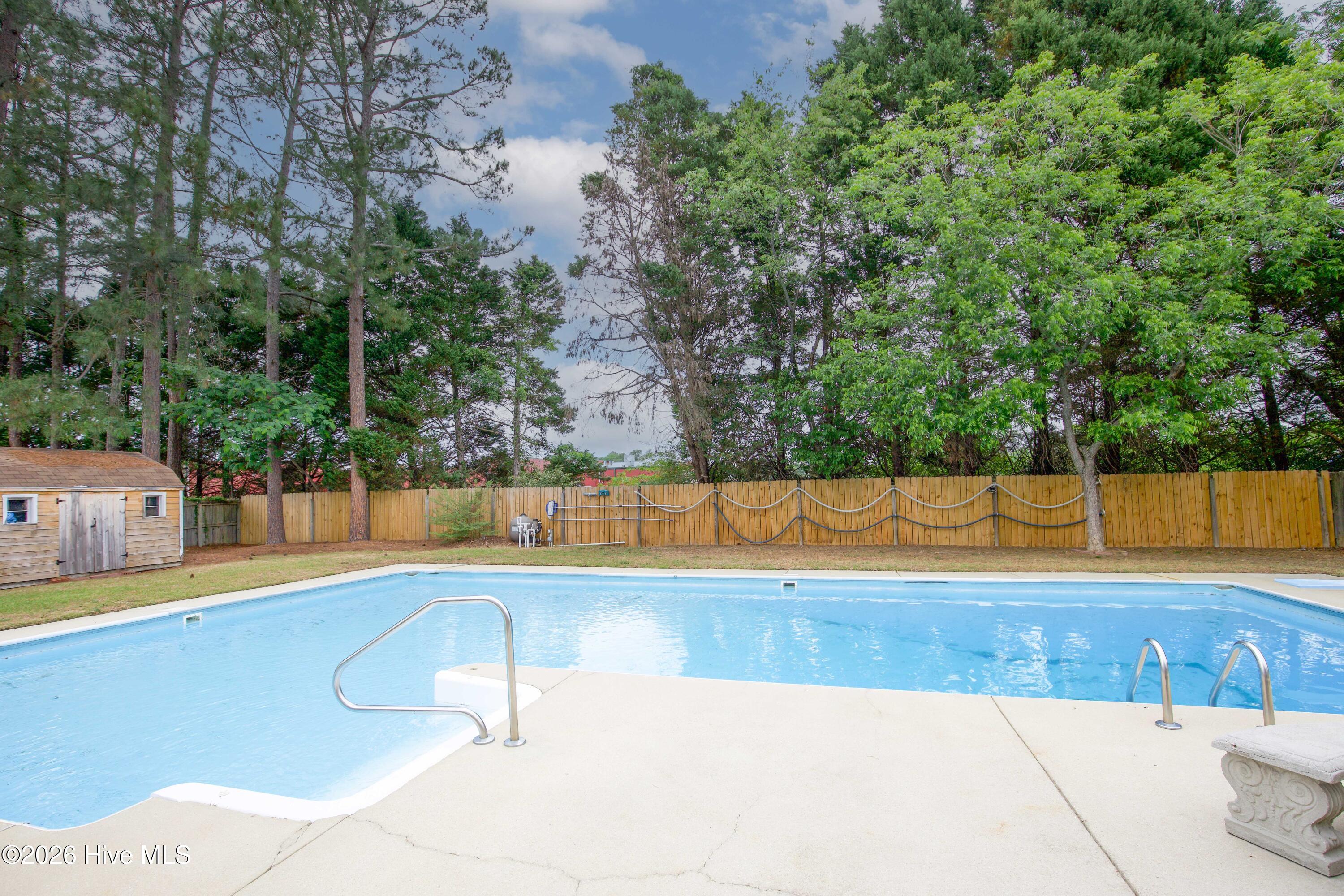 Spacious pool and patio area designed for outdoor enjoyment, entertaining, and relaxation. This inviting backyard setup features ample concrete patio space, mature shade trees, and a fully fenced yard creating a private atmosphere perfect for summer gatherings and everyday outdoor living. Ideal for buyers searching for move-in ready Fayetteville homes with lifestyle-focused outdoor amenities near Fort Bragg.