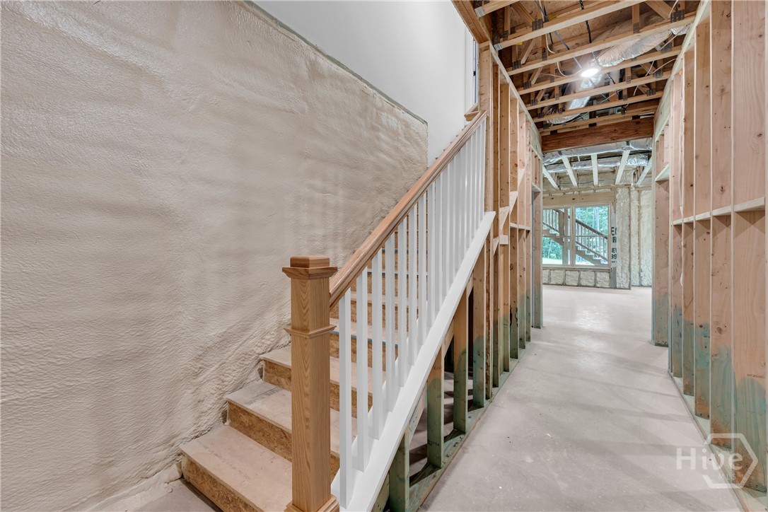 Unfinished lower level featuring a framed staircase with wood newel post and white balusters