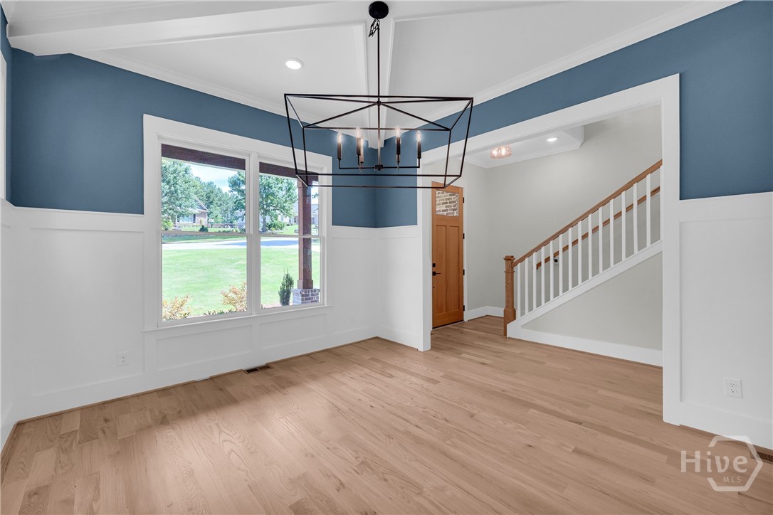 Spacious interior featuring wood-finish flooring, wainscoting, and a modern geometric chandelier in the Dining Room