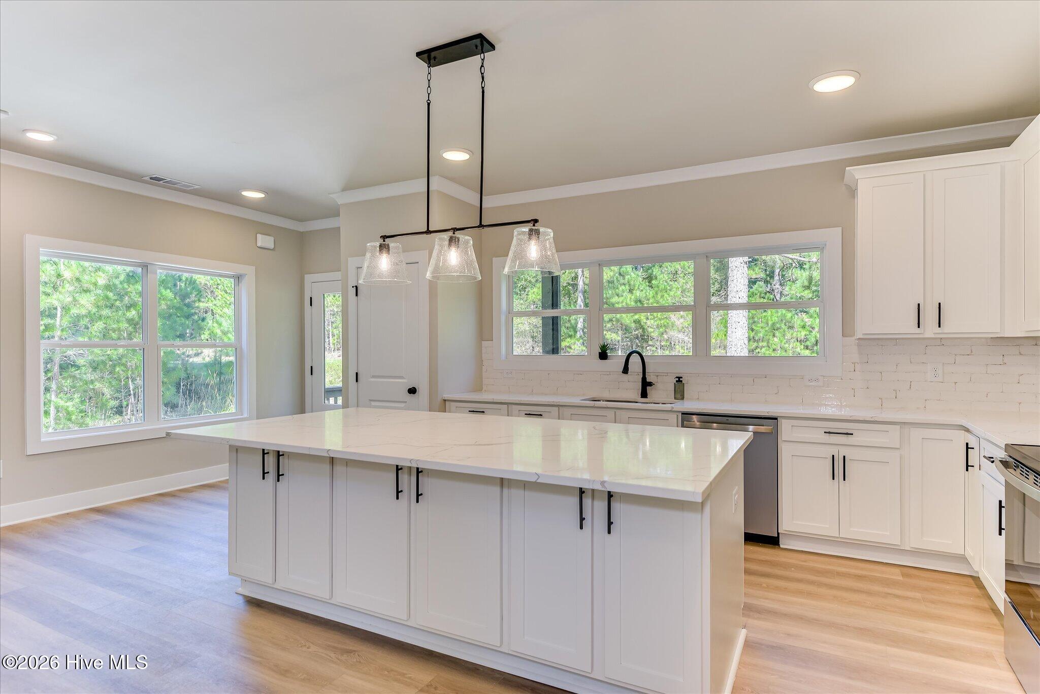 Well-equipped kitchen with quartz countertops, stainless steel appliances, oversized quartz island with lots of storage, and a pantry.