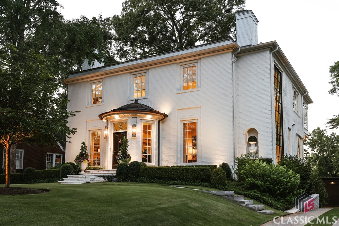 This custom-designed Regency inspired home, envisioned by Schutze Award-winning architects Spitzmiller and Norris, was completed in 2021. Nestled among trees to maximize views of downtown Athens, the campus, Sanford Stadium, and the Coliseum, it epitomizes luxury and sophistication. Built to exacting standards with steel framing and a brick exterior, every detail both inside and out reflects comfort and elegance.The curved foyer entrance features true curved windows leading to the living and dining spaces, which offer views through a steel and glass rear wall opening onto an oyster paver patio shaded by ancient oak trees. A parlor room with a fireplace, adorned with a Francois and Co finished mantle, and a steel and glass partition wall delineates the space from the main living area. The dining room showcases a bespoke built-in dry bar with antique mirrored glass fronts.The kitchen is a culinary masterpiece with a large center island, custom cabinetry from Made in Monroe, and top-tier appliances including SubZero and Wolfe. An antique mirrored backsplash complements the 6-burner range with pot filler, alongside unique spice storage. The scullery kitchen features a separate prep sink, refrigerator and freezer drawers, coffee bar, and appliance storage, all set against honed Olympic Danby marble countertops. The flooring throughout the home includes Francois and Co French Oak wood laid in a herringbone pattern in the two foyers.The breakfast room and great room open onto a picturesque rear patio, creating seamless indoor/outdoor entertainment spaces reminiscent of an English garden. A three-story full glass wall along the side of the house frames the open staircase with steel railings, providing access to all levels.Upstairs, the owner's suite offers tranquil views and a luxurious bathroom with heated limestone flooring, a custom dressing vanity, a full marble shower, and a slipper tub. The secondary bedroom features a lavish bathroom with heated tile flooring and a full wet room with a Japanese soaking tub. A third room upstairs currently serves as a closet, with potential for easy conversion into a third bedroom with an ensuite bathroom. Additionally, there's a light-filled yoga/exercise room with a full mirrored wall and workout flooring.The terrace level includes an additional bedroom and a stylish bathroom, ideal for a private guest suite. A spacious great room opens to a screened porch with a fireplace overlooking the private backyard. The terrace level also features an attached one-car garage and an impressive laundry/mud room with concealed machines, a sorting closet, built-in desk, and a separate sink and dishwasher for entertaining.The private backyard oasis features turf grass, carefully selected plantings, and thoughtful connectivity between the porch and patio. A sophisticated cistern system manages drainage efficiently. The detached two-car garage includes a lift system capable of accommodating up to three additional cars. The entire house is serviced by an elevator and boasts a fully integrated tech/sound/lighting system with automation for lights, blinds, and music, as well as comprehensive security systems, central vacuuming, and wiring for a whole house generator.This property offers a rare opportunity for the most discerning buyer.