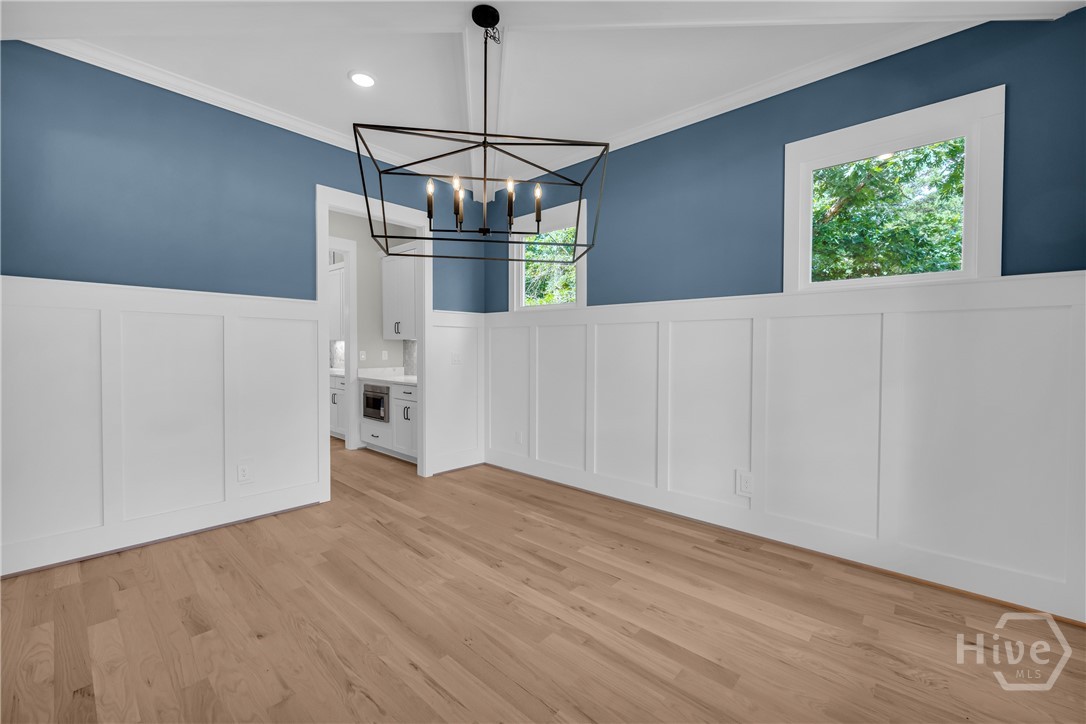 Hardwood flooring complements the wainscoting and blue walls in the beautiful Dining Room
