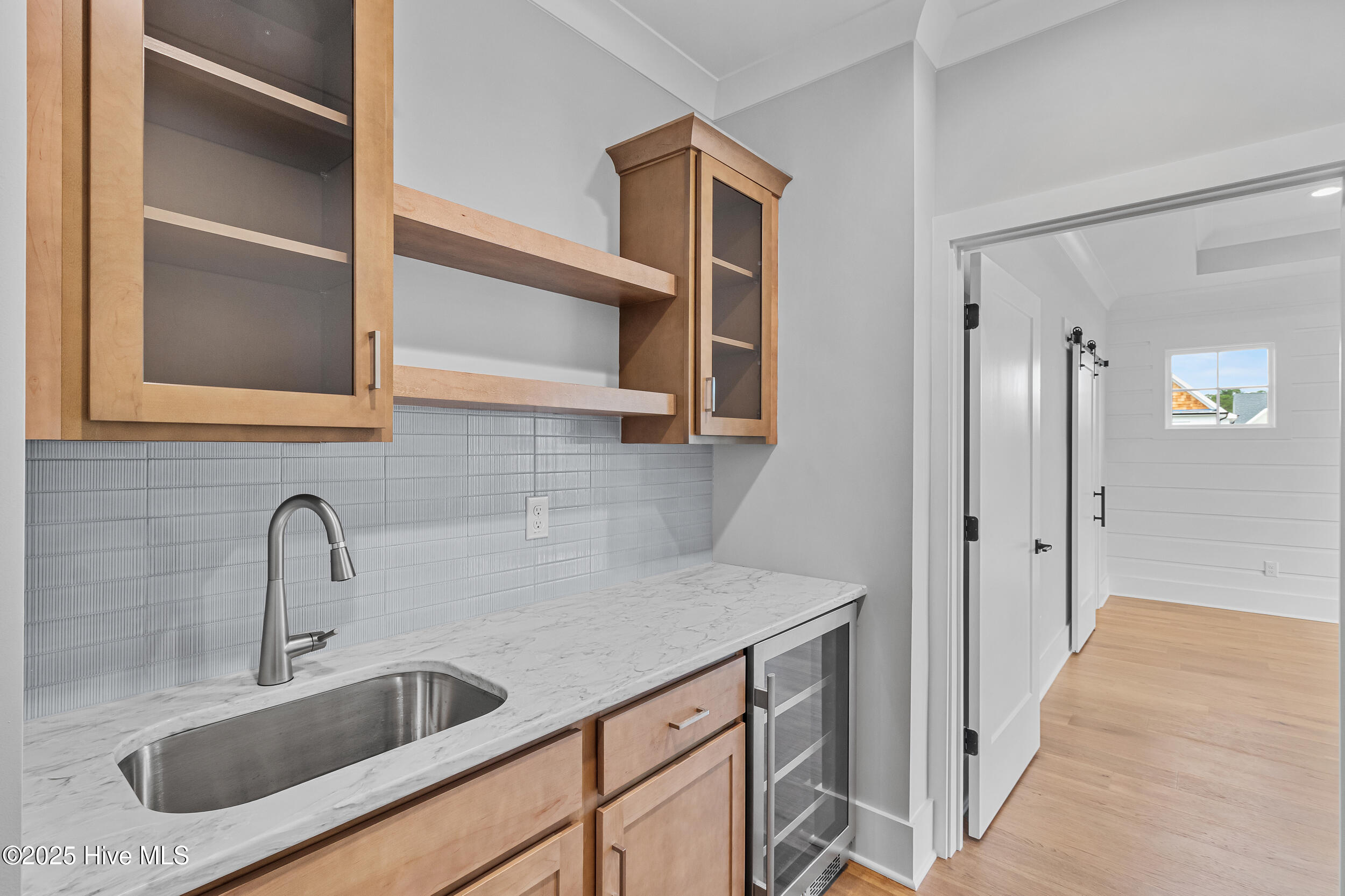Wet bar with sink, mini fridge, and cabinets