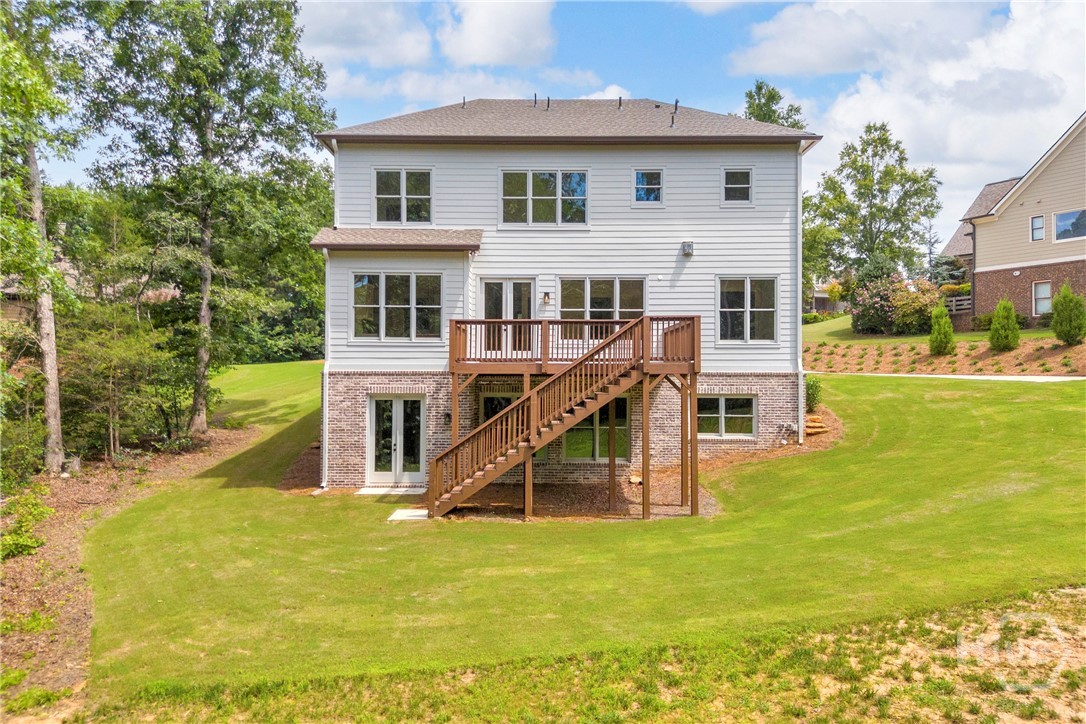 Rear exterior featuring white horizontal siding, a multi-level wood deck, and a walk-out lower level with brick accents