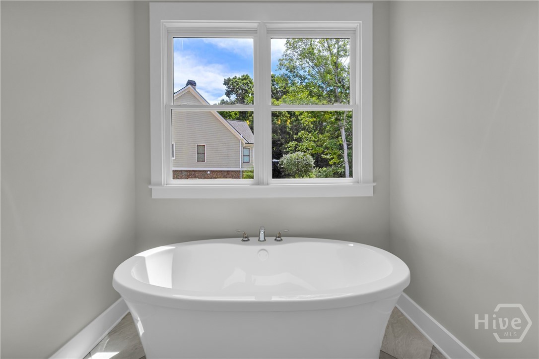 Freestanding soaking tub with polished chrome fixtures set beneath a double-hung window