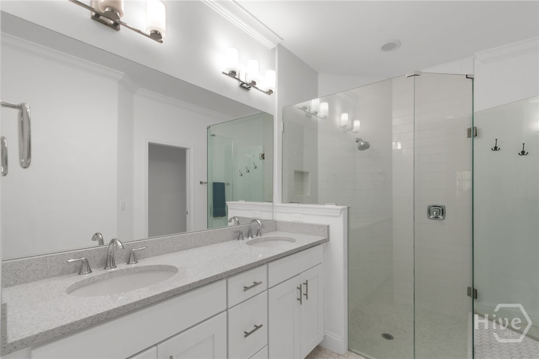 Double sink vanity, fully tiled shower with frameless glass enclosure, and separate water closet