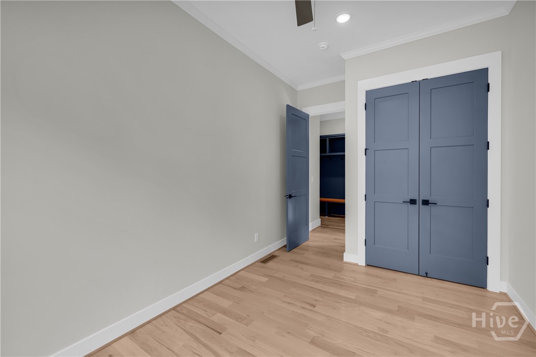 Light-filled guest bedroom on main featuring a double-hung window, wood-finish flooring, a ceiling fan, recessed lighting, and crisp white trim