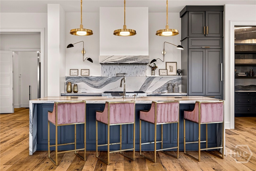 Kitchen is a culinary showpiece featuring Wolf, Cove and Subzero professional-grade appliances, navy island and marble backsplash The kitchen’s layout centers around a statement island, offering generous prep space and visual symmetry. A dramatic marble backsplash and layered cabinetry create depth, while pendant lighting defines the culinary zone. Designed for both function and elevated presentation.