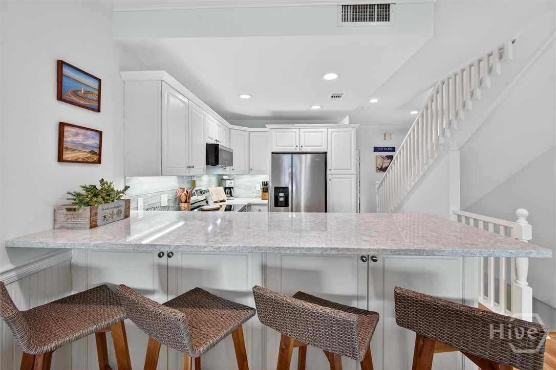 Gorgeous, well-equipped kitchen with quartz countertops, stainless steel appliances and tile backsplash.