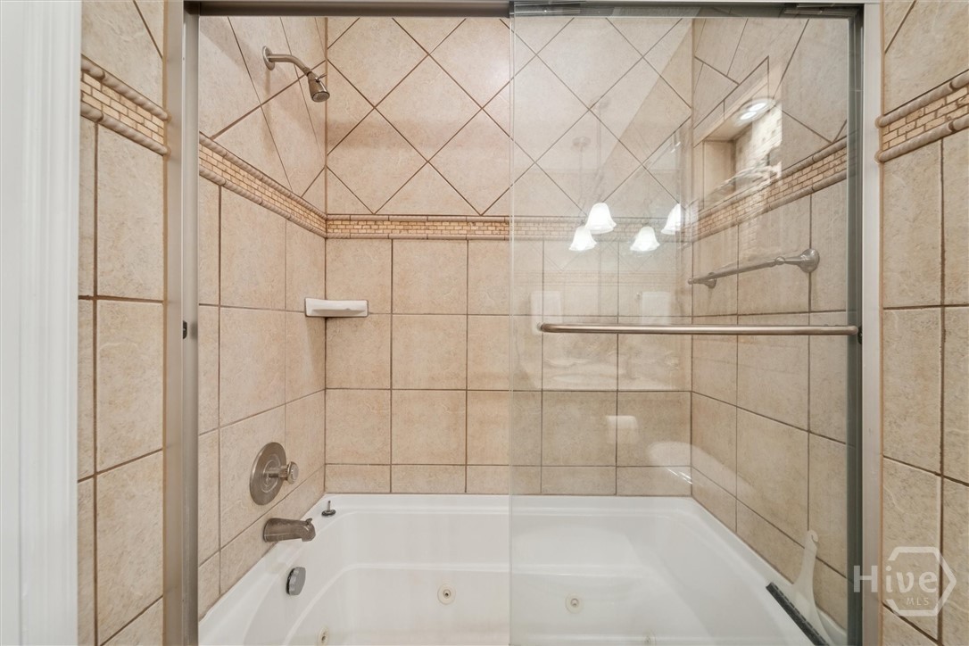 A tiled tub/shower with glass doors completes the primary bath.