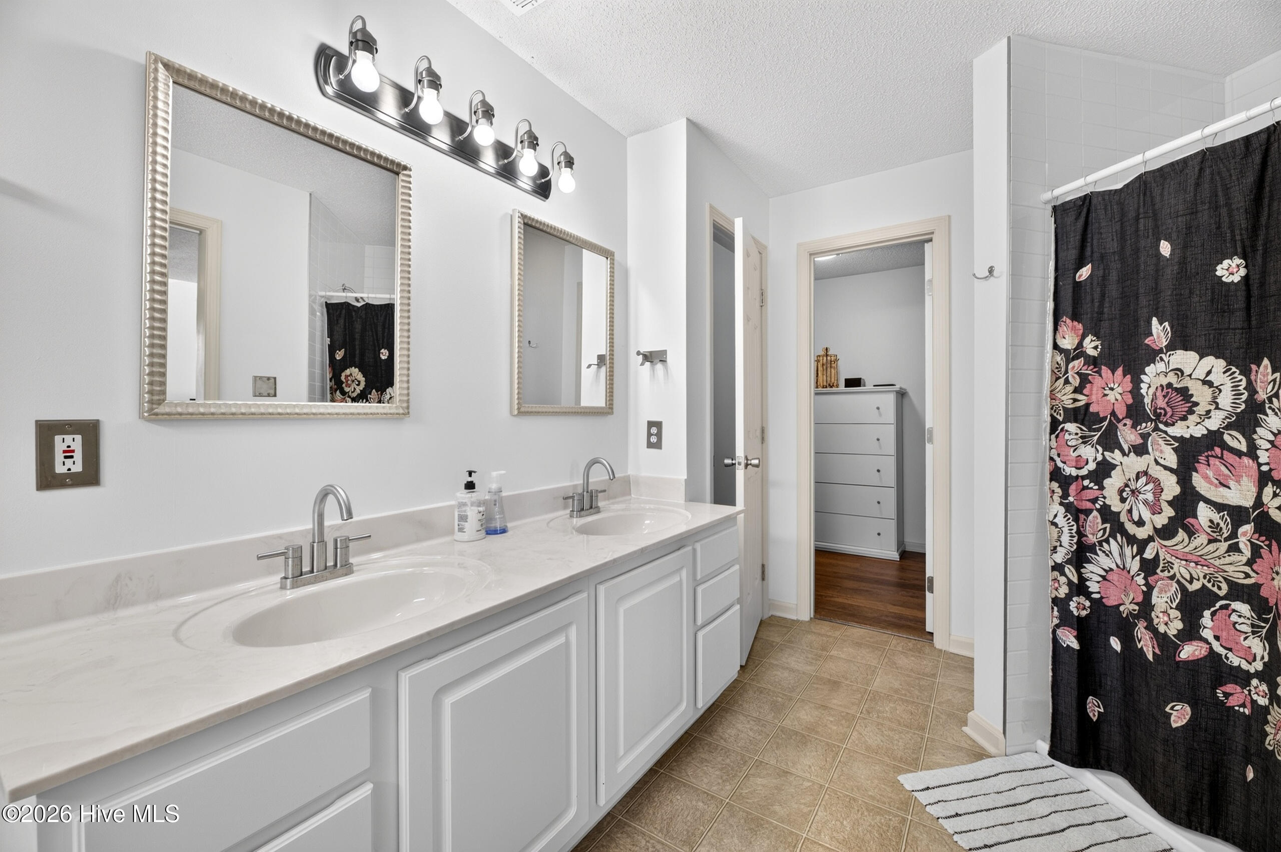 Primary bath includes tile shower, dual sinks, water closet