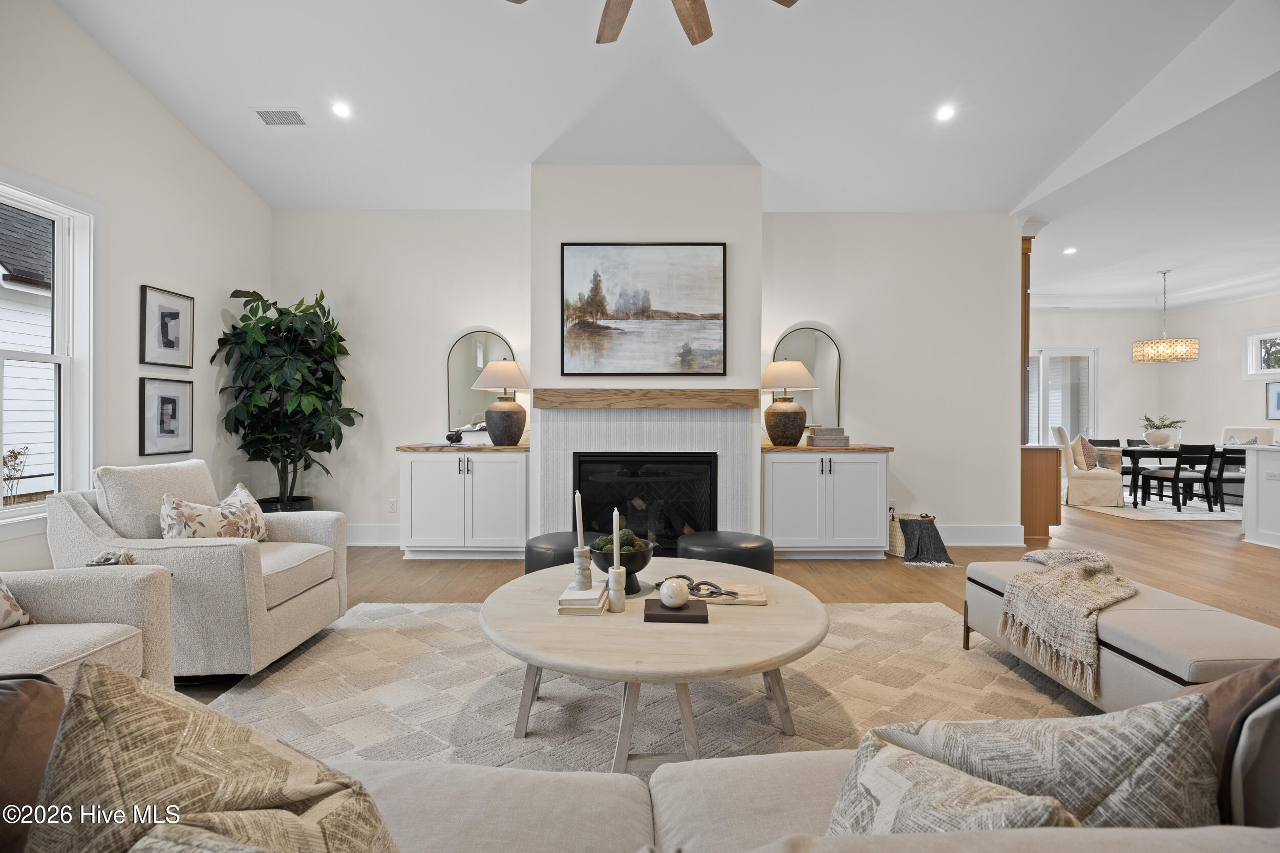 Living room with vaulted ceilings, custom built-ins, and a natural gas fire place