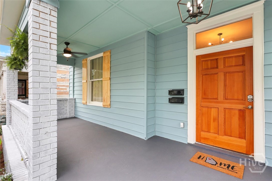 Inviting covered front porch with classic brick accents and a warm wood entry door.