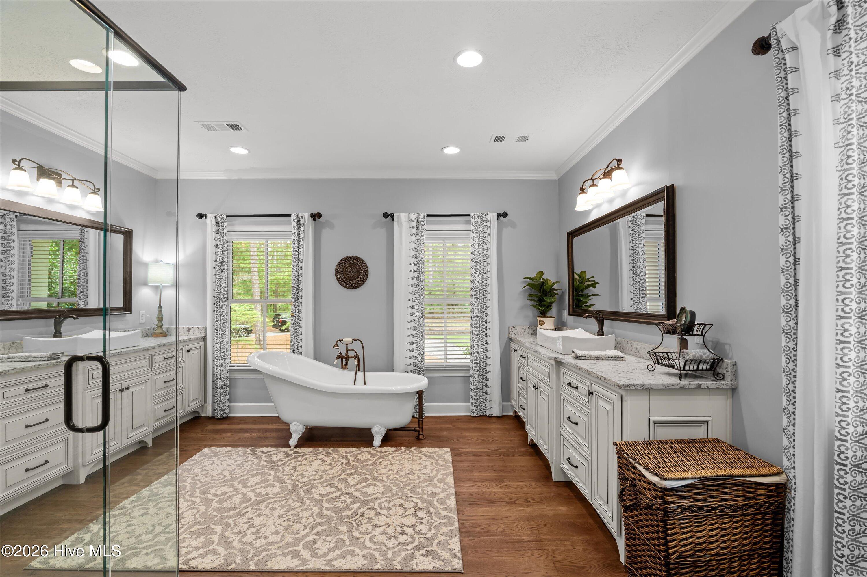 Master bath with claw foot tub, oversized tiled shower, and two vanity areas