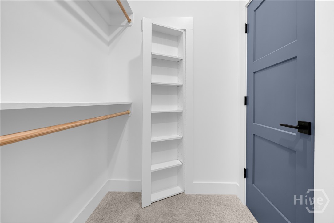 White built-in shelving unit, natural wood-finish hanging rods, and a three-panel door with matte black hardware