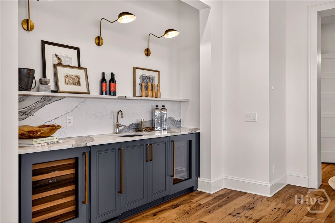 Built-in bar niche with marble and wine cooler. A custom-designed bar niche integrates seamlessly into the main living space, offering both elegance and utility. Framed by rich cabinetry and marble surfaces, the layout includes a built-in wine cooler and sink, ideal for entertaining. A refined architectural feature that enhances both form and function.