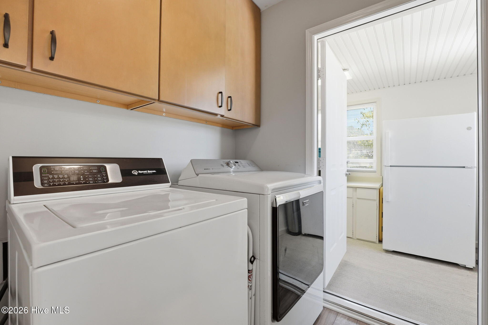 Laundry room with entrance to a large pantry storage area.