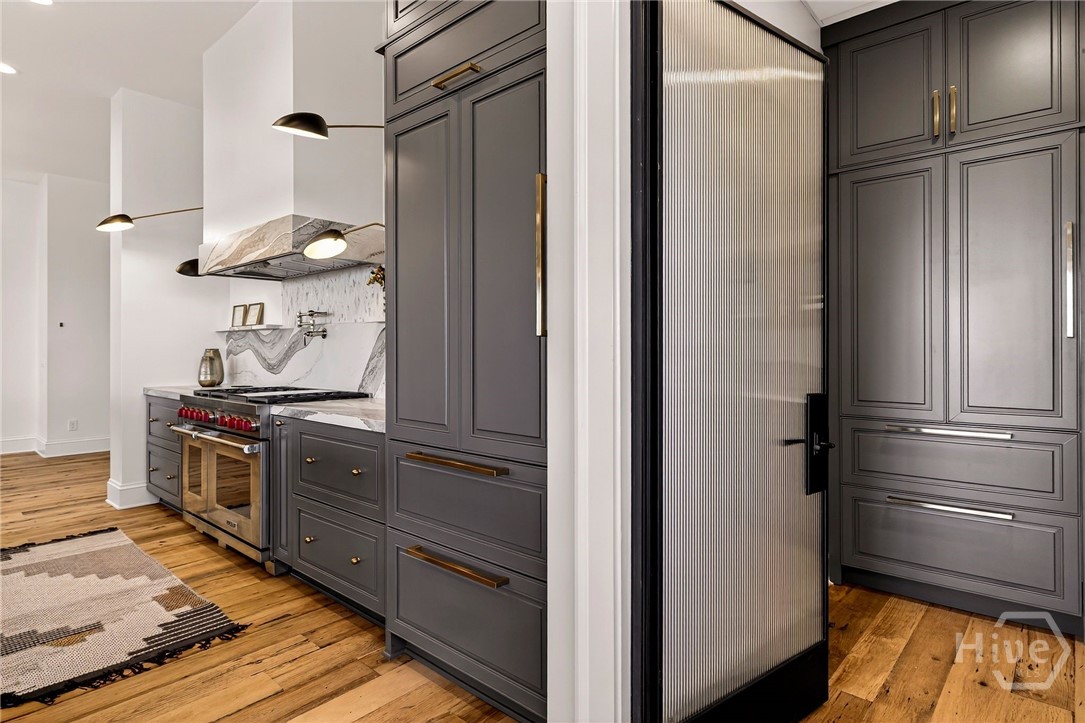 Kitchen with integrated appliances and frosted glass door. This culinary space is designed with precision, featuring integrated appliances and a streamlined layout. Dark cabinetry and marble surfaces create visual depth, while the frosted glass door offers discreet access to pantry or utility zones. A refined blend of functionality and architectural elegance.