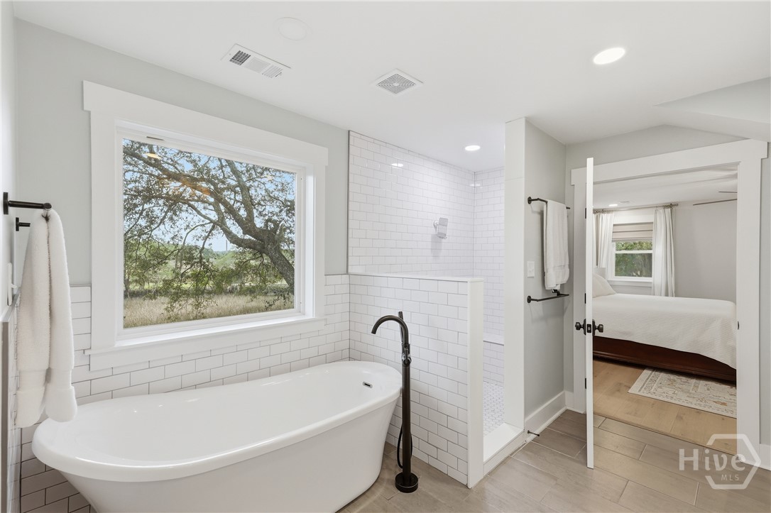 Primary suite with separate garden tub with marsh views and large tiled shower