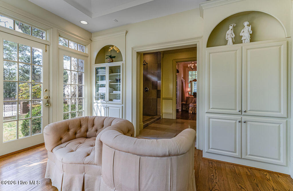 Two dressing rooms with built-ins and walk-in closets. Primary bath with chandelier, marble counters, Jacuzzi tub, built-in cabinetry, oversized stone-tile walk-in shower, and French doors to the grounds.