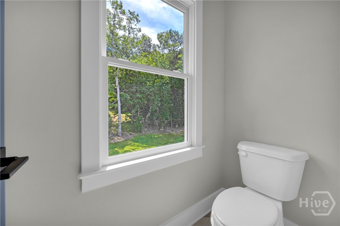 Window with natural light and white trimwork, complemented by light gray wall paint and a white toilet