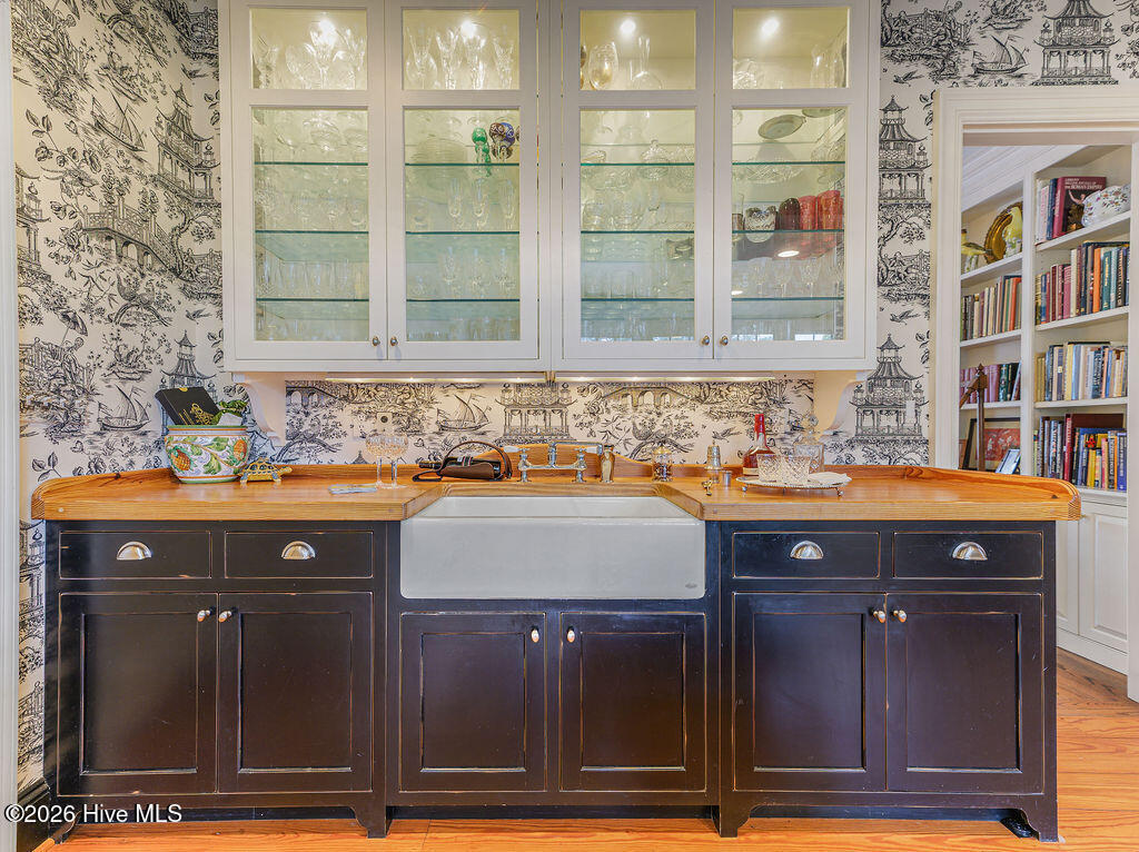 The butler’s pantry pairs glass front cabinets, a farm sink and butcher block counter with custom storage, extending the kitchen’s thoughtful craftsmanship and utility.