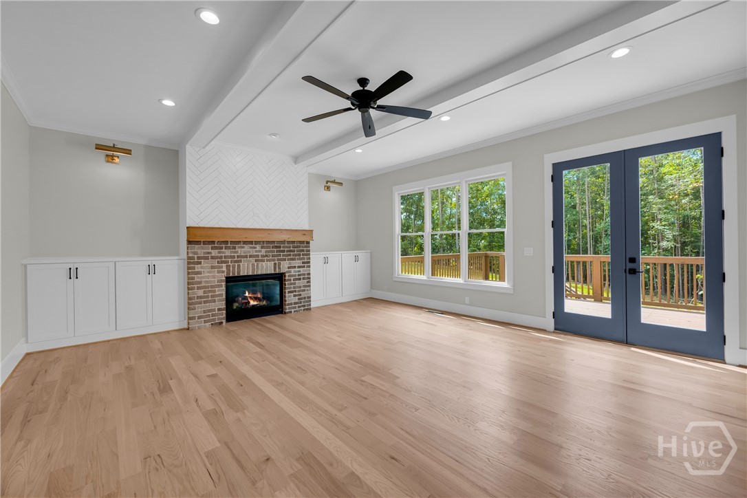 Spacious family room featuring light wood-finish flooring, a brick gas log fireplace with a wood mantel, built-in cabinetry, recessed lighting, and a ceiling fan
